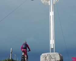 Foto Mountainbiker neben Gipfelkreuz